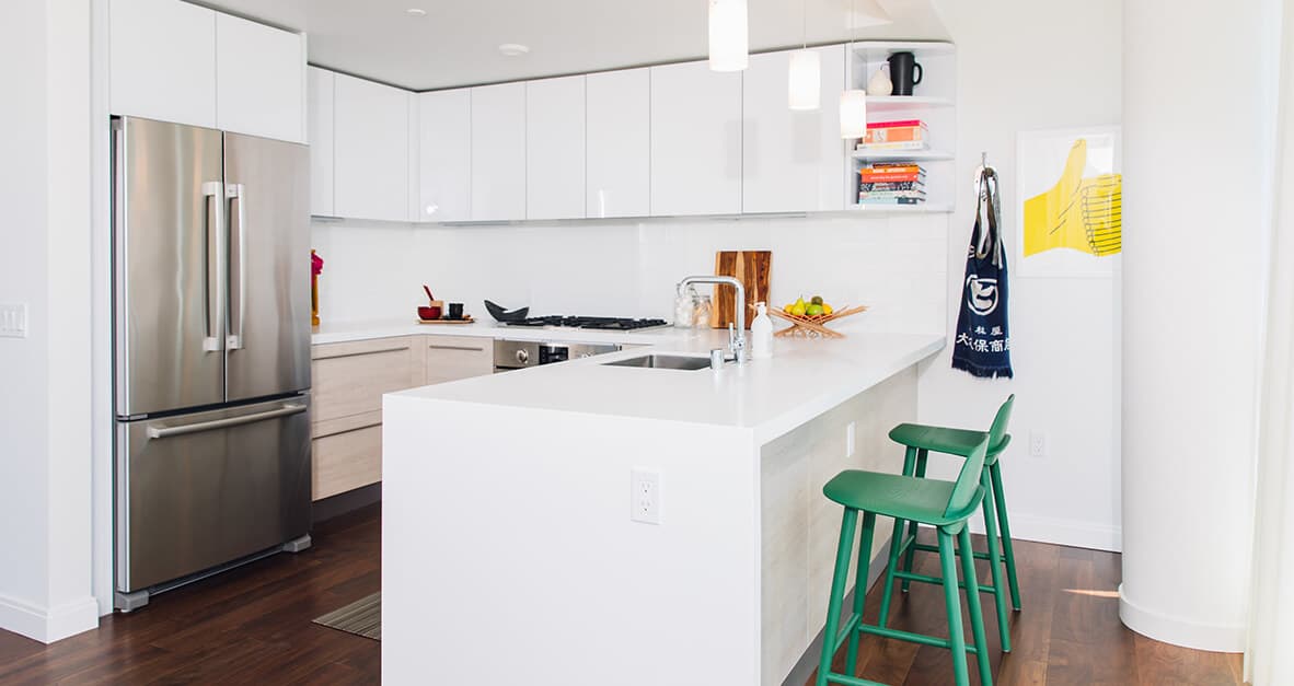 Kitchens are furnished with stainless steel Bosch appliances, sleek countertops, modern cabinets, and hardwood floors throughout the space. 