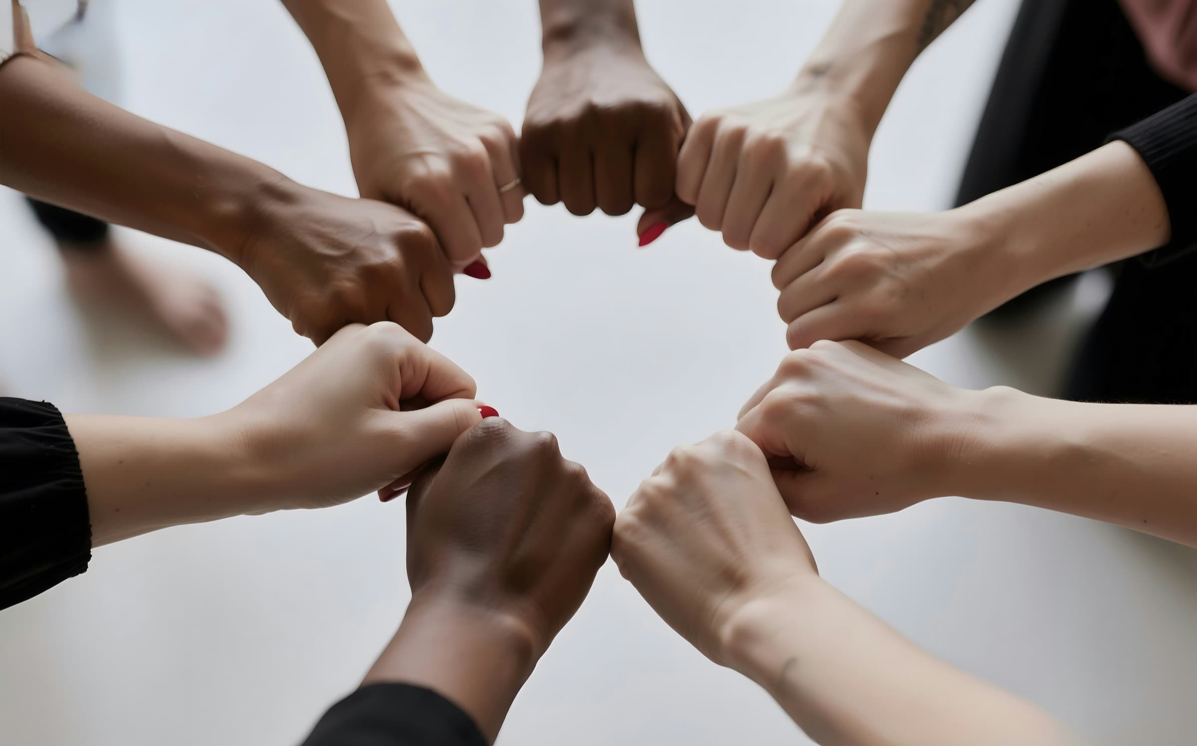 A circle of hands from above, each fist linked to the next