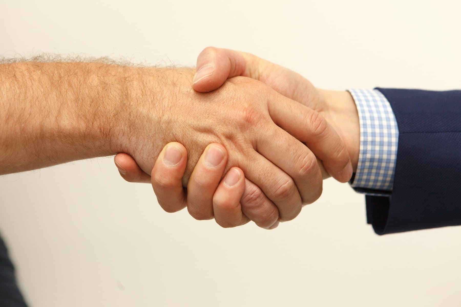 Two people shaking hands, one in a navy suit and gingham shirt