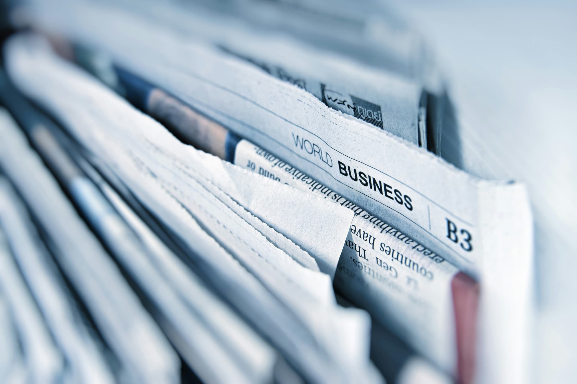 A row of folded newspapers, the world business section in focus