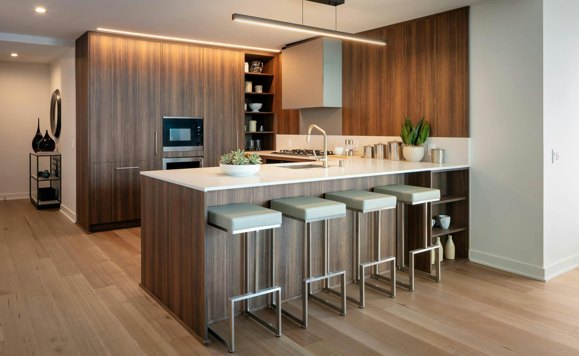 The kitchen in a MIRA residence looks clean and innovative in design, with ivory-colored Caesarstone countertops, custom cabinetry, and plenty of pantry and island storage. Photo courtesy of the MIRA website. 