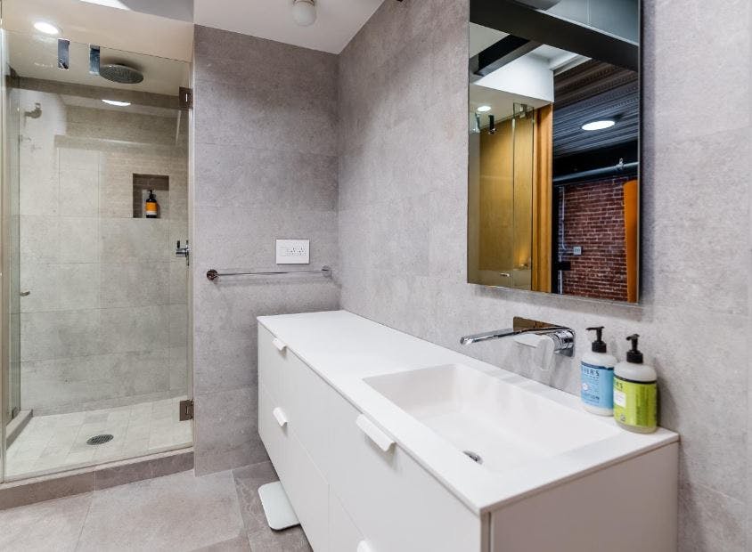 Tiled bathrooms with an industrial aesthetic work together to boast a capacious yet sleek appearance. 