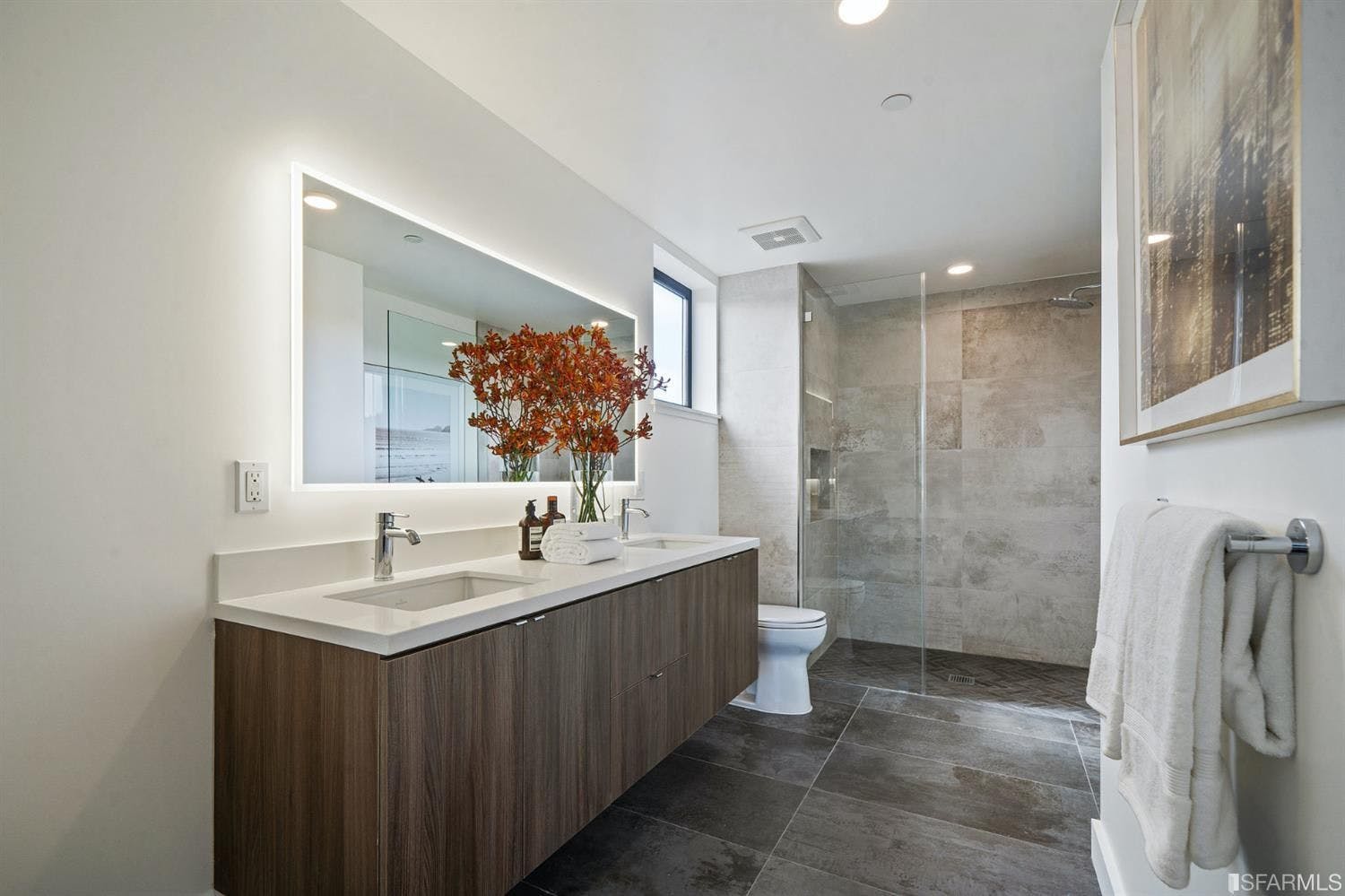 Quartz countertops, floating vanities, and dark tile flooring work together to create a sleek, modern atmosphere in bathrooms of Mission Modern.